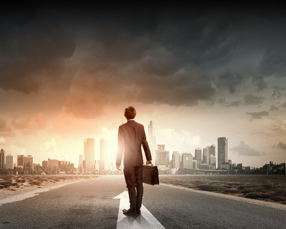 Rearview of businessman with suitcase standing on the road